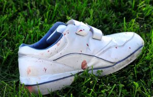 A blood=splattered sneaker beside the Chevy.