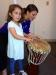Darlington caption: Preschool music teacher Stevie Neale shows preschool student Aisling Donahue, of Wilmington, how to play a drum during a Native American unit.
