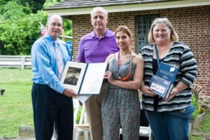 State Rep. Stephen Barrar presents a flag and citation to Nadia Barakat and Kendal Reynolds of the Chadds Ford Historical Society. State Se. Dominic Pileggi looks on.