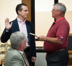 Robert Sage, standing on left, takes the oath of office administered by School Board President Vic Dupuis. Director Steve Simonson looks on.