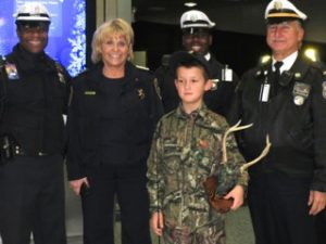 Alex Collins, 9, is flanked by Chester County Sheriff Carolyn 'Bunny' Welsh and members of the Philadelphia Police Department at the airport.