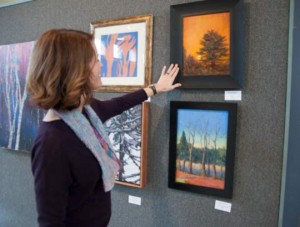Chester County Art Association Director Karen Delaney admires the detail in Melissa McNett's "Sunset." Delaney said it's a personal and effective view that makes her want to see more of the artist's work.