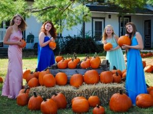 Pageant participants Clarisse Cofrancesco (from left), Shannon White, Lauren Chamberlain, and Lexus McKinney pose with pumpkins at Barnard's Orchard, which supplies the pageant and fair with decorations.