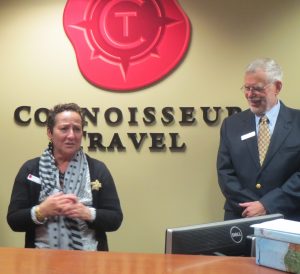 Cathy Hagle (left) addresses the crowd at the grand opening of Connoisseur Travel in Kennett Square, as her husband, George Hagle, who co-founded the business with her, looks on.