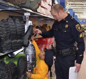 A young shopper looking for boots for his father benefits from the height of his shopping assistant: Deputy Sheriff Adam Sibley.