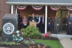 Standing at a podium in front of the memorial for Chester County's fallen officers, Steve Plaugher, past president of FOP Lodge No. 11, concludes the program.