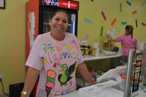 Noelia Scharon shows off the shop's brightly-colored t-shirts, which were designed by her nephew.