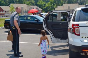 Kennett Township Police Chief Lydell Nolt watches a group of  children activate the sirens in his police vehicle, which is locked in park.
