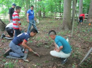 Students begin digging around a stone believed to be a headstone of one of the residents laid to rest in the cemetery. 
