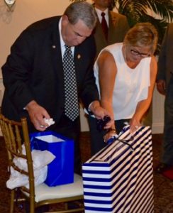 Former Police Chief Edward A. Zunino gets assistance from his wife, Lois Zunino, with unwrapping a street sign in his honor.