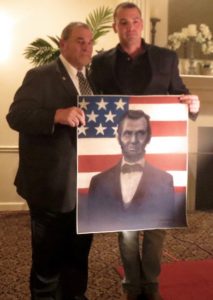 The former police chief (left) accepts a painting of Abe Lincoln done by Fred McCarthy, who says he believes Zunino possesses many of Lincoln's exemplary traits.