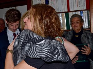 Karyn Pless (right) embraces Peggy Gusz. Behind them are Will Pless (left) and her mother-in-law, Jeanne Pless, 