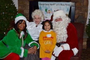A young shopper poses with Margery Gonzales (from left), one of Santa's elves. Mrs. Claus, and the big man himself.